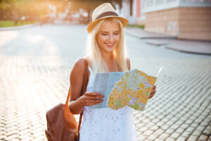 Happy tourist woman on vacation with map visiting a new city