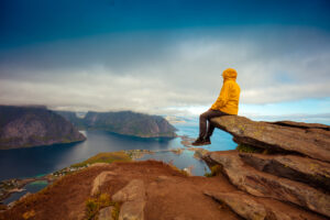 Male tourist sitting on the cliff in a beautiful mountain landscape