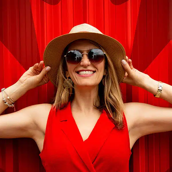 Woman wearing read and a hat in front of a Canadian leaf symbol