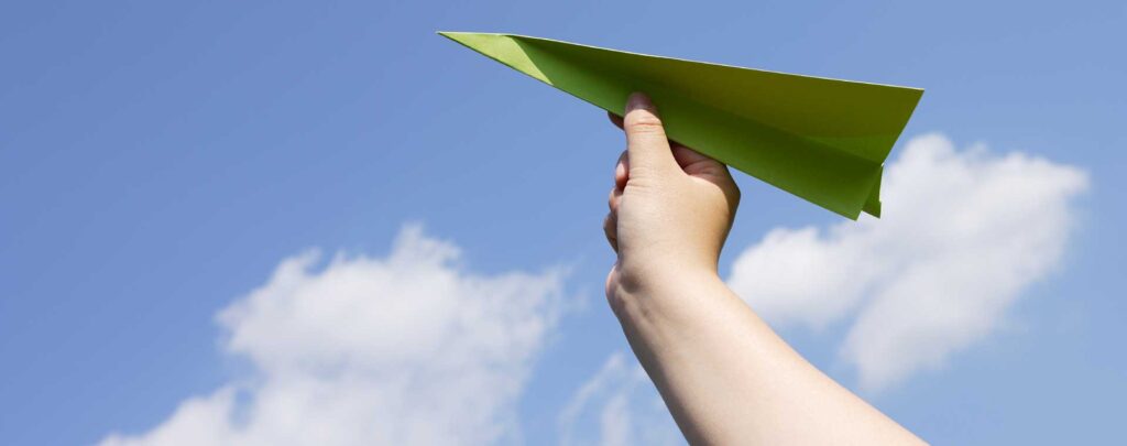 Paper airplane about to be launched on a beautiful blue background