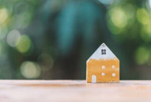 Small model house on wooden table with a natural sunlit background