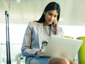 Business woman working on her laptop while at an airport relocating