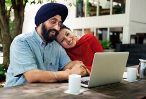 An Indian couple looking at a laptop and enjoying their new home