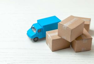 Miniature moving truck beside stack of large boxes