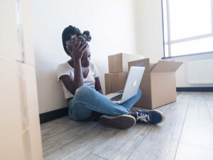 Young woman looking at her computer during a stressful move during peak moving season