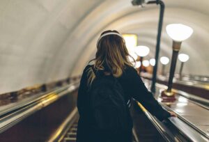 Expatriate Woman with headphones on an escalator in the Subway