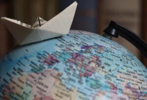 A small paper boat sitting on a world globe