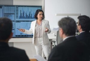 Executive standing in front of a group of people explaining some charts
