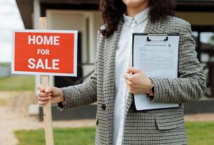 Un agent immobilier tenant une pancarte « À vendre » et un contrat de vente