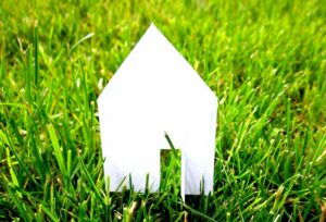 Paper cutout of a house sitting on grass: Why Relocation Policies Do Not Behave Like Other HR Policies